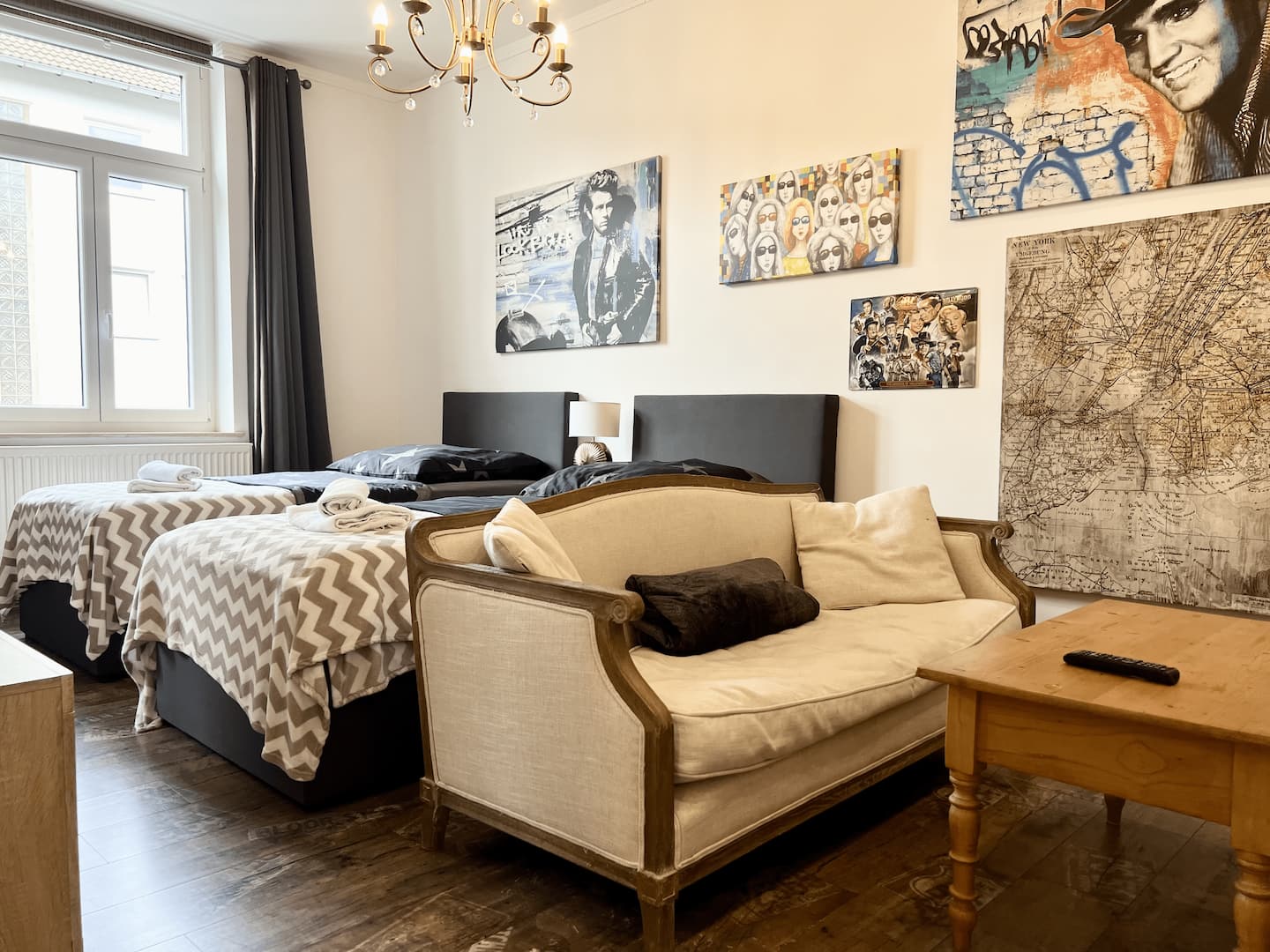 Living and sleeping area of the NewYork Suite with sofa, chandelier and pop art