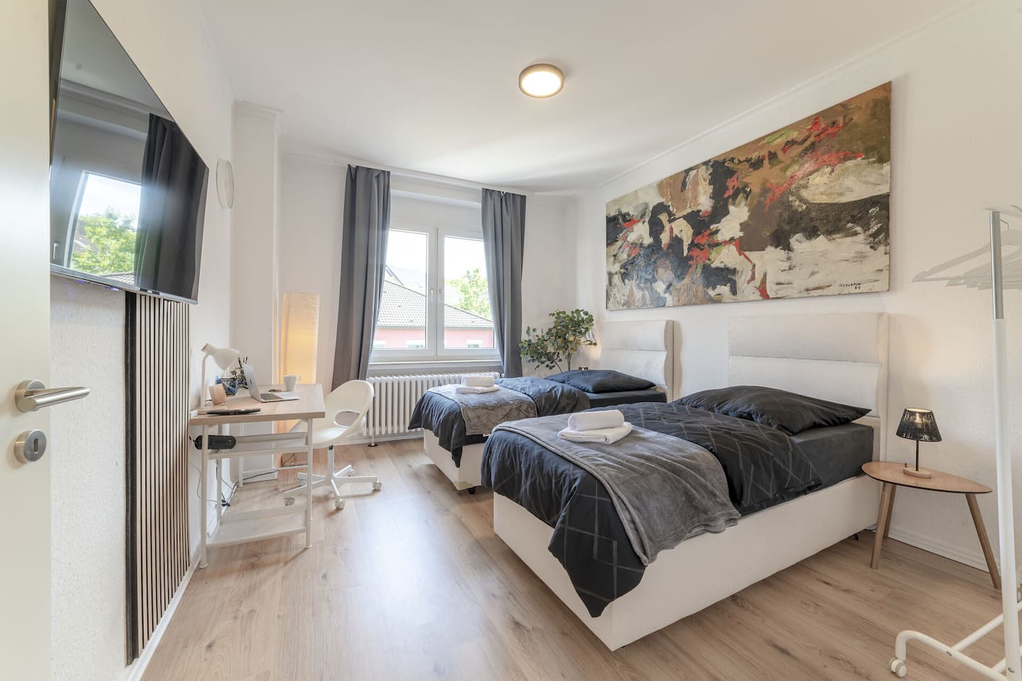 Bright bedroom with two box-spring beds and a large-format artwork in the Prime Art Gallery Apartment