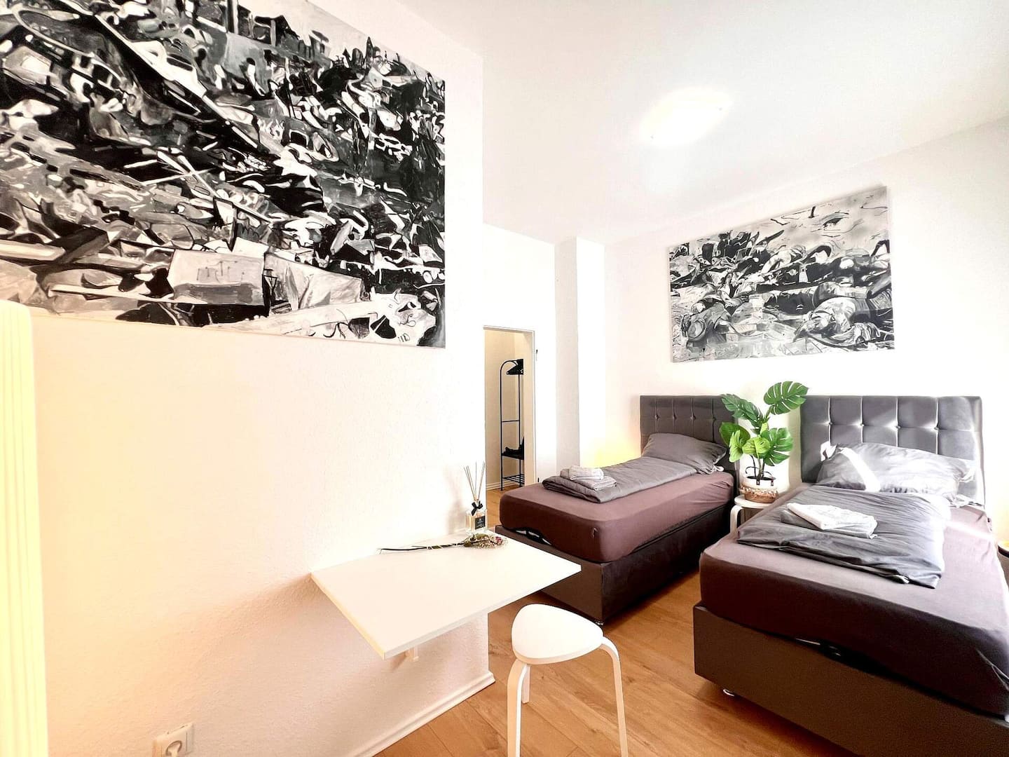 Modernes Zimmer mit zwei Einzelbetten, Wandkunst und Esstisch im City-Apartment in Essen