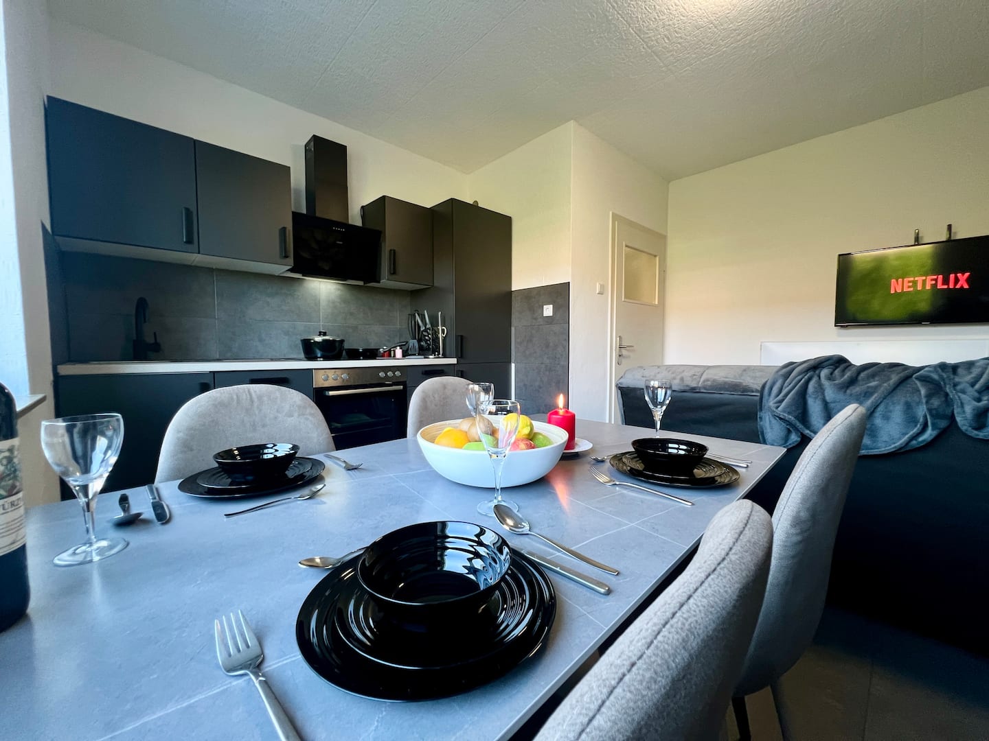 Moderne schwarze Küche mit gedecktem Esstisch und Netflix-Smart-TV im Apartment Katernberg