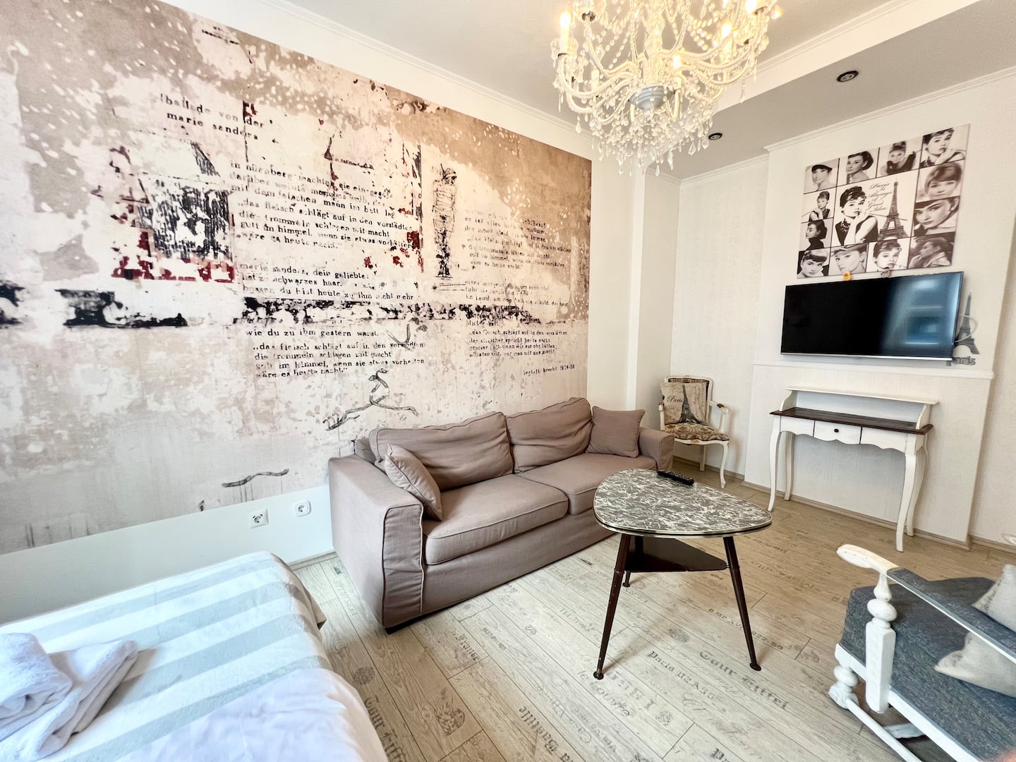 Wohnbereich der Paris Suite mit Kronleuchter, Sofa und Audrey-Hepburn-Galerie